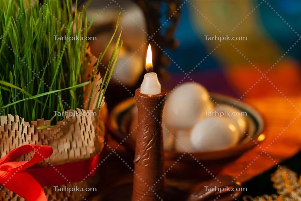 شمعی در حال سوختن بر روی سفره ای جشنواره نزدیک به جوانه گندم و آینه، نشانه های سنتی نوروز ایرانی