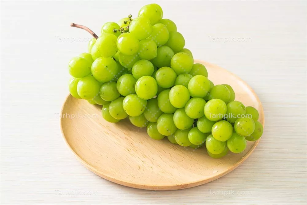 انگور سبز تازه بر روی بشقاب چوبی - تجربه ای طبیعی و دلپذیر