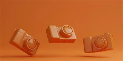 دوربین دیجیتال نارنجی بر روی پس زمینه نارنجی - مفهوم فناوری با رندرینگ سهبعدی