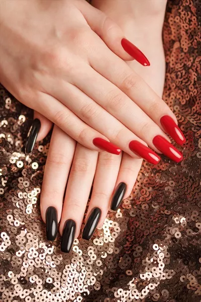 دستهای یک دختر جوان با طراحی ناخنهای قرمز و سیاه