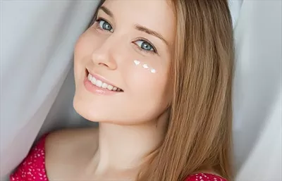 زنی زیبا با کرم مراقبت از پوست بر روی صورتش