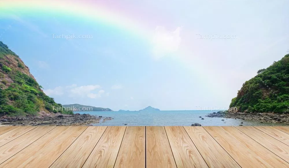 منظره ای دلنشین از یک میز چوبی خالی با نمای سواحل استوایی و رنگین کمان زیبا بالای دریا