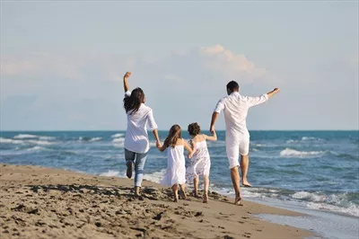 خانواده جوان و شاد در حال لذت بردن از روزی خوش در ساحل