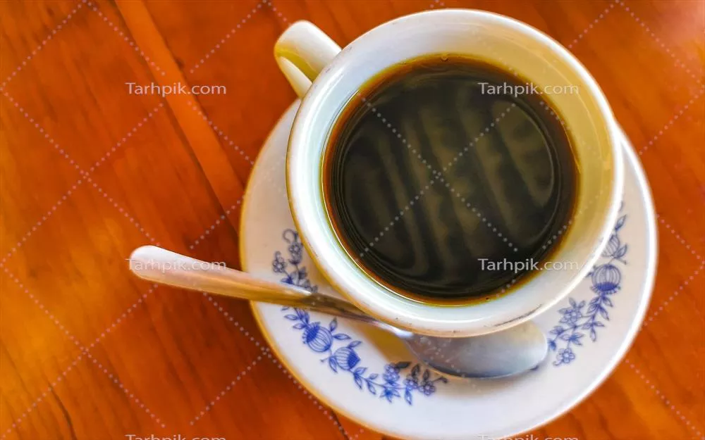 فنجان آبی و سفیدی با قهوه سیاه بر روی یک میز چوبی در مکزیک