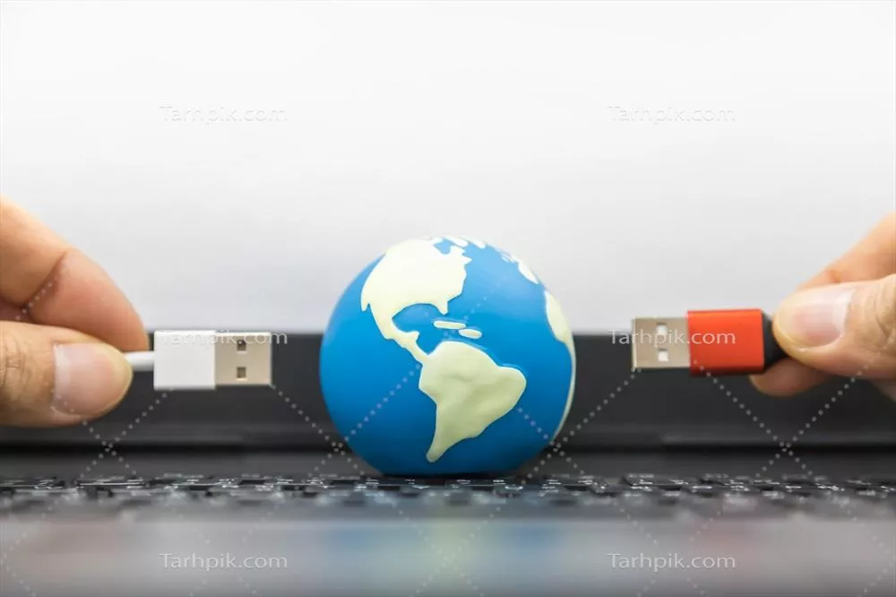 مفهوم ارتباطات، کامپیوتر و فناوری جهانی: نمای نزدیک از کره کوچک در دست و کابل USB بر روی کیبورد لپتاپ