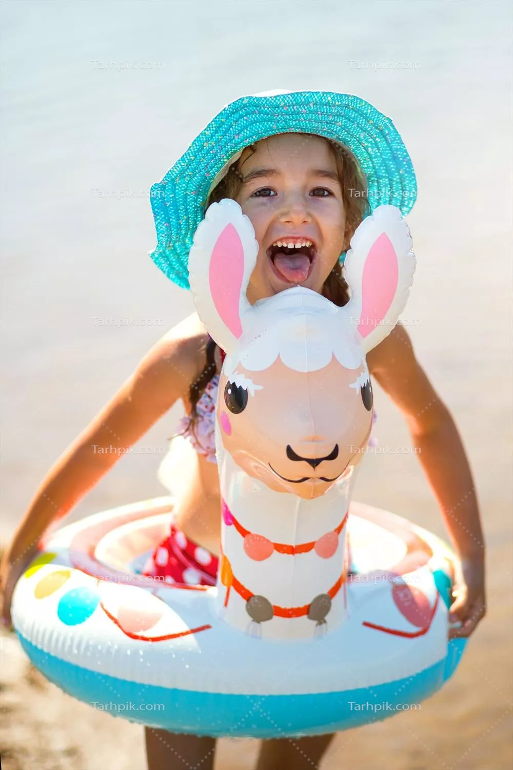 دختری با کلاه در ساحل، در حال شنا با حلقه بادی شبیه لاما