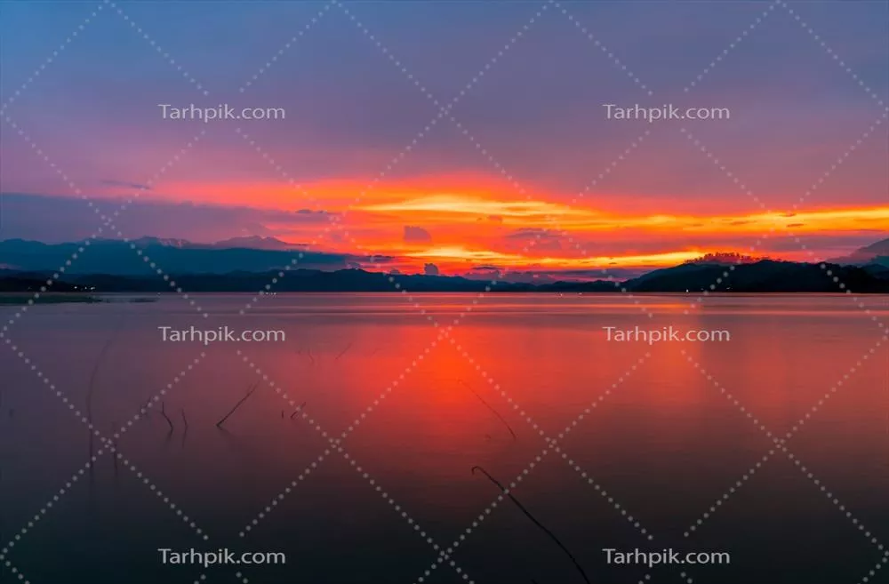غروب باشکوه آسمان سرخ و نارنجی در کوهستان و دریاچه با زیبایی طبیعی