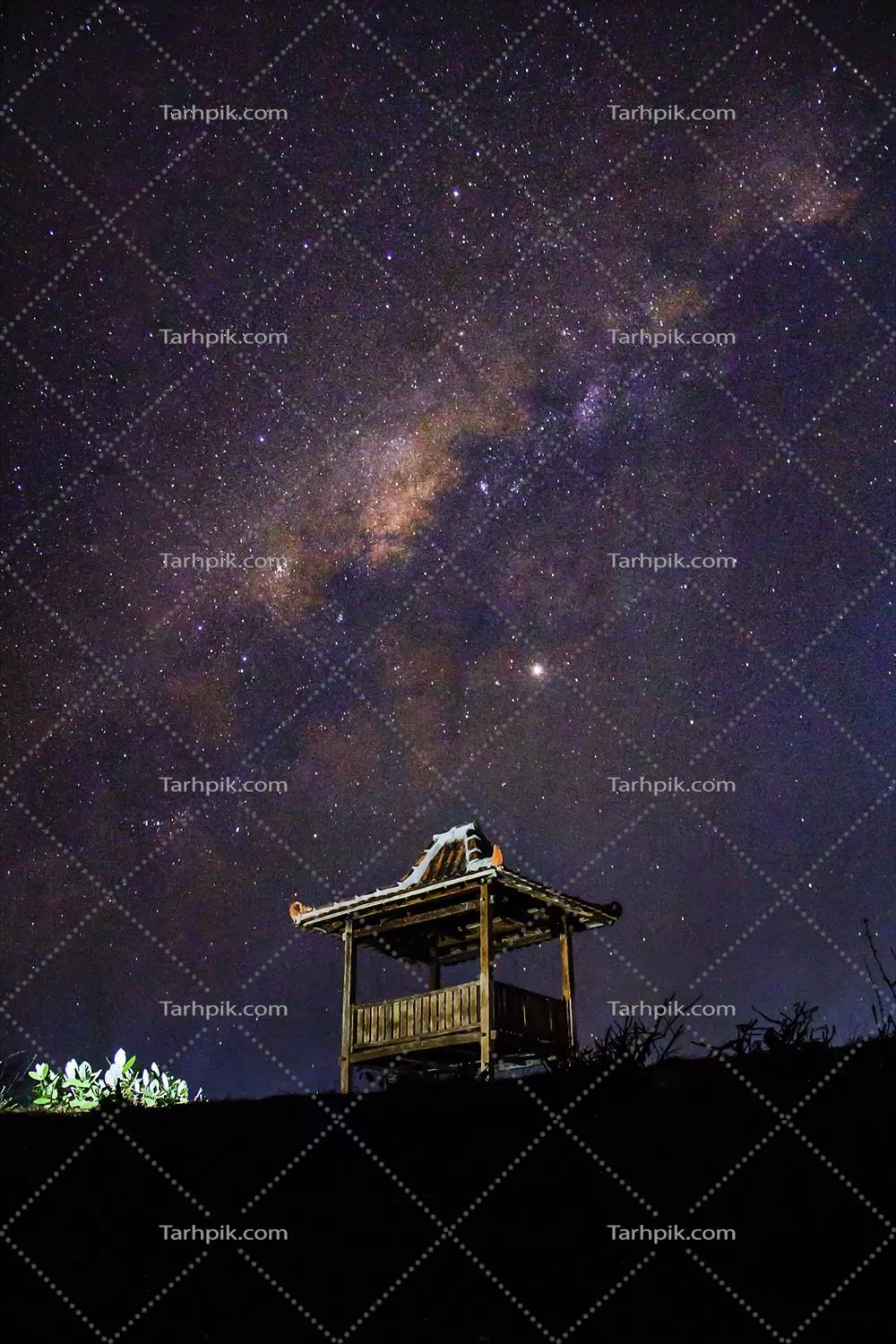 کهکشان راه شیری در آسمان بالای خانه چوبی در حال ظهور است