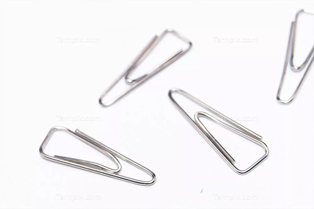 چهار گیره کاغذ نقره‌ای پراکنده شده بر روی زمینه سفید - لوازم اداری