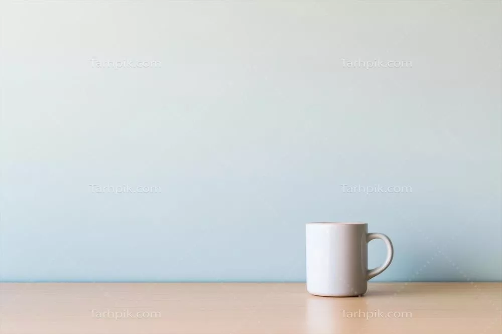ماگ ساده و سفید روی میز چوبی با پسزمینه آبی ملایم