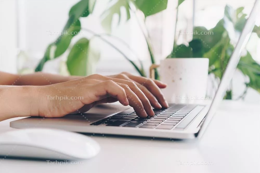 شخصی با لپتاپ در حال مطالعه بر روی میز کار خود