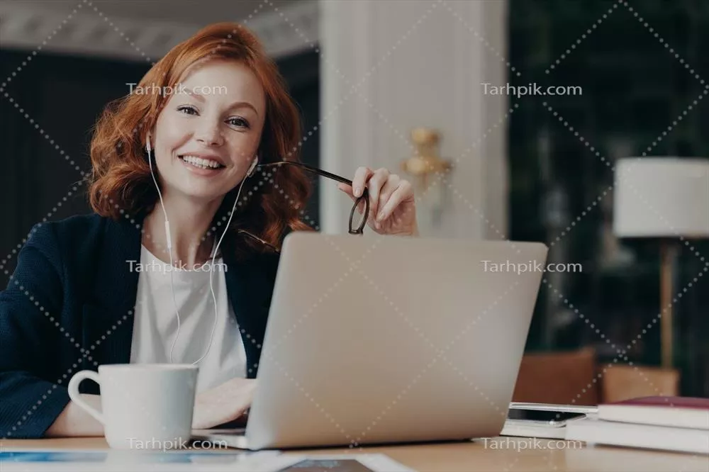 زنی جوان و شاد با موهای زنجبیلی در حال فکر کردن به ایده‌های جدید برای کار