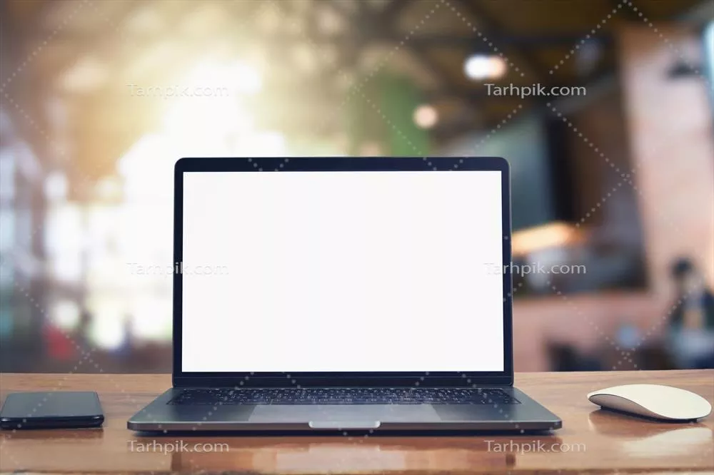 لپتاپ با صفحه سفید و موبایل روی میز در پس زمینه کافه