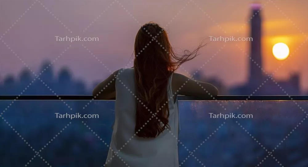 زن در حال تماشا و لذت بردن از غروب آفتاب از بالکن در مرکز شهر شلوغ