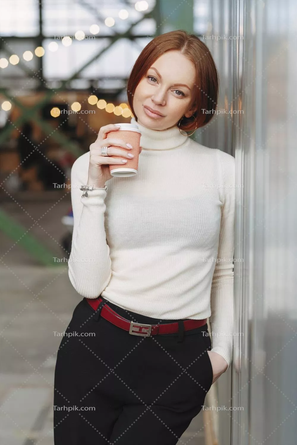 تصویر عمودی از زن جوان فکر کن با ژاکت سفید و شلوار سیاه که قهوه بیرون بر را در دست دارد و در فضای باز خیال پردازی میکند