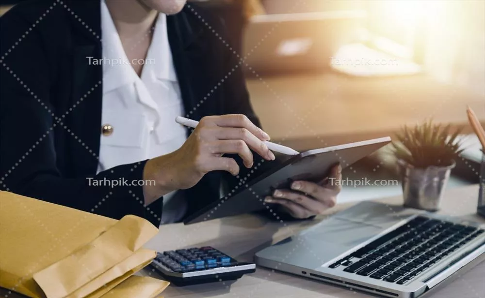 زنی حسابدار که با استفاده از کامپیوتر و ماشین حساب در حال کار است