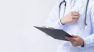 پزشک با گوشی پزشکی در روپوش سفید در حال نوشتن سوابق پزشکی