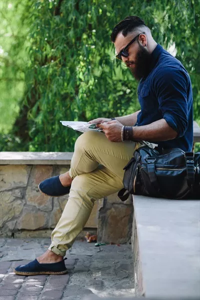 مرد با ریشی که به نقشه نگاه میکند و مسیر خود را مییابد