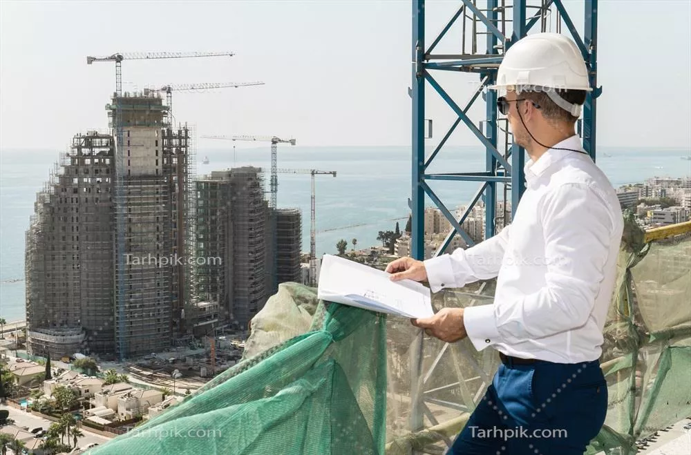 معماری و تجارت: مهندس با کلاه سخت و نقشه‌های ساختمانی در کنار دریا