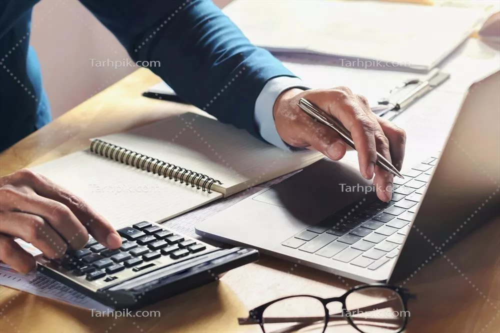 مرد بازرگان در حال کار بر روی میز با استفاده از ماشین حساب و کامپیوتر در دفتر – مفهوم حسابداری و مالی