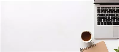 لپ‌تاپی بر روی میزی در کنار یک فنجان قهوه، طراحی شده با فناوری هوش مصنوعی مولد