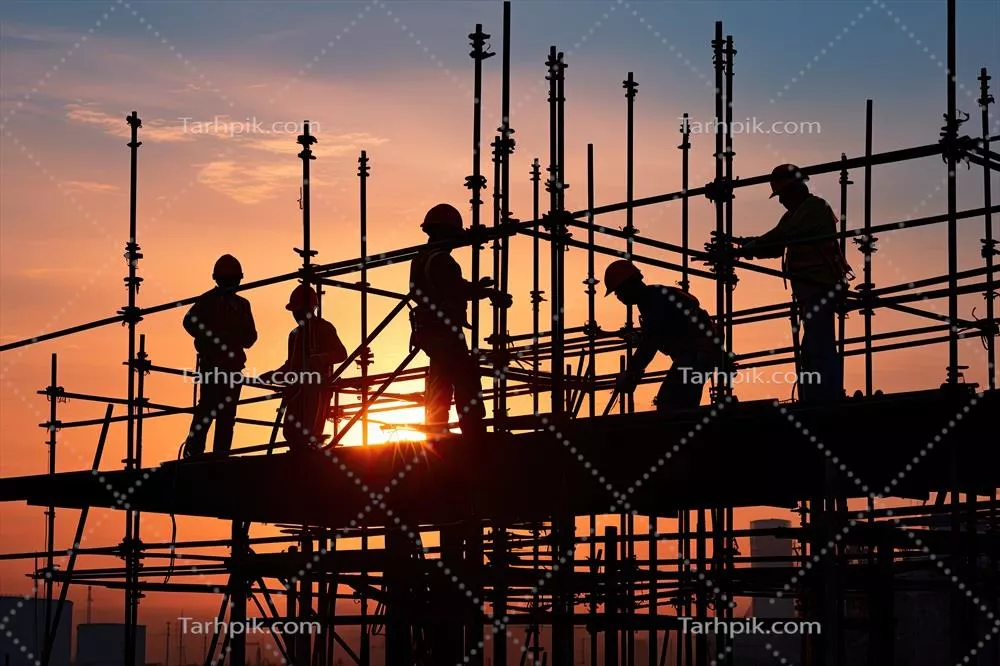 سایه‌ واضح کارگران ساختمانی در حال کار بر روی داربست در غروب آفتاب