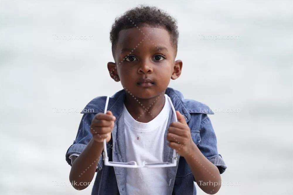 پسر مختلطنژاد آفریقایی و آسیایی در حال بازی در ساحل با شادی و لبخند