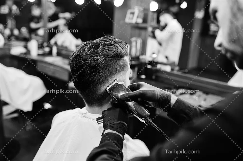 آرایشگر مشغول کار بر روی مرد خوش قیافه با ریش در آرایشگاه