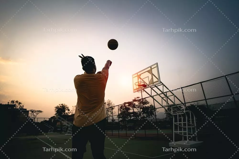 سیلوئت بازیکن بسکتبال در غروب خورشید - تصویر جذاب از پرتاب توپ