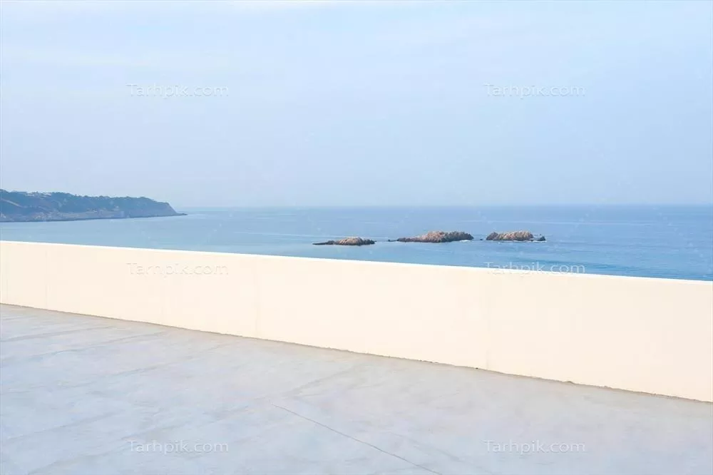 نمای دریایی مدرن از یک تراس مینیمالیستی با پس‌زمینه سواحل و صخره‌های اقیانوس