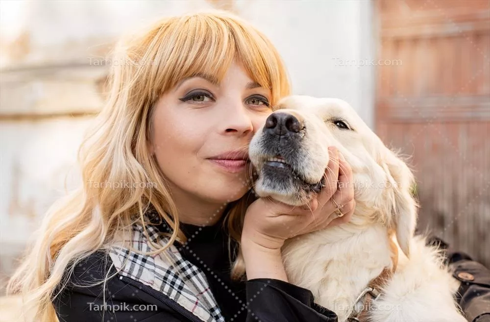 زنی با موهای بلوند که در حال در آغوش گرفتن سگ رتریور خود است