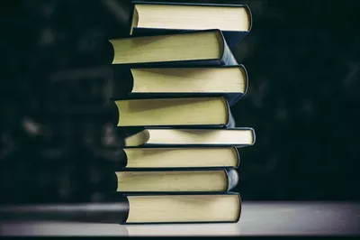 کتاب‌ها بر روی یک میز در دسته‌ای از کتاب‌ها قرار دارند