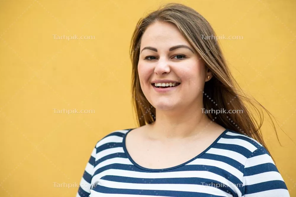 زن چاق خوشحال که در حال ژست گرفتن در یک پسزمینه نارنجی است