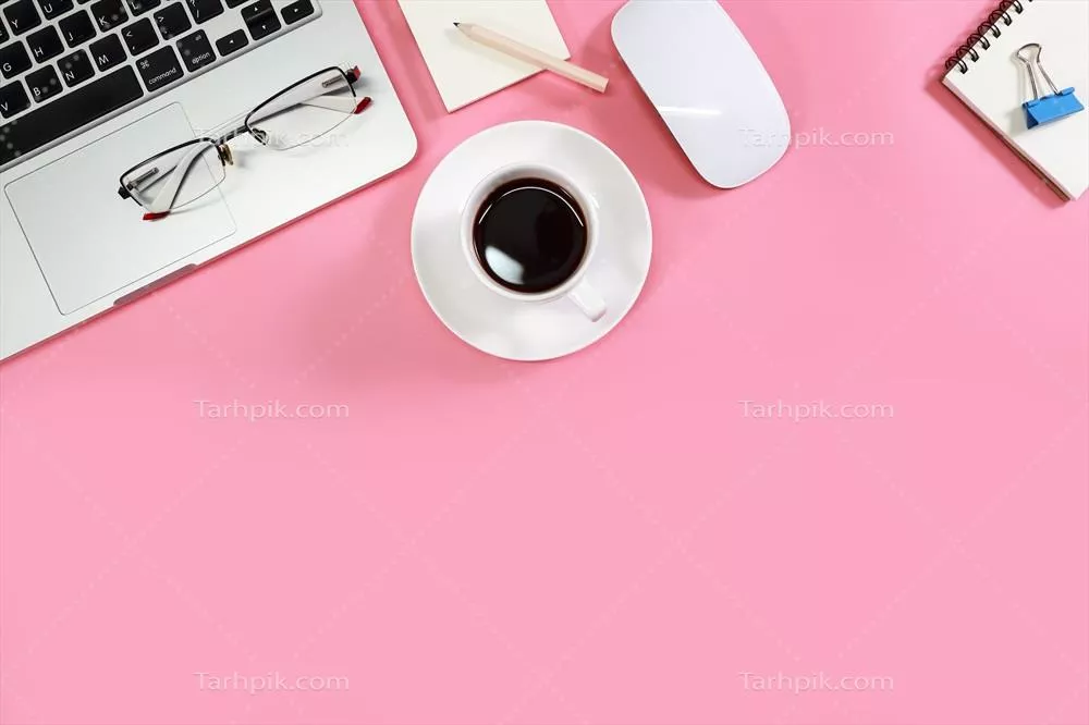 تصویری از فضای کار با لوازم اداری و لپتاپ بر روی میز به رنگ صورتی