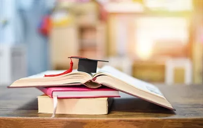مفهوم آموزش با کلاه فارغالتحصیلی بر روی کتاب روی میز چوبی