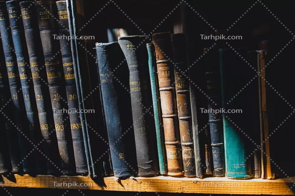 کتابهای قدیمی بر روی قفسه در کتابخانه زیر تابش نور آفتاب