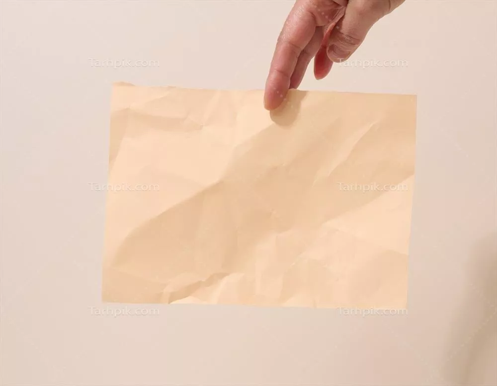 دست زنانه که برگه مچاله شدهای را بر روی زمینهی بژ نگه داشته است - محلی برای یادداشتها و اعلامیهها