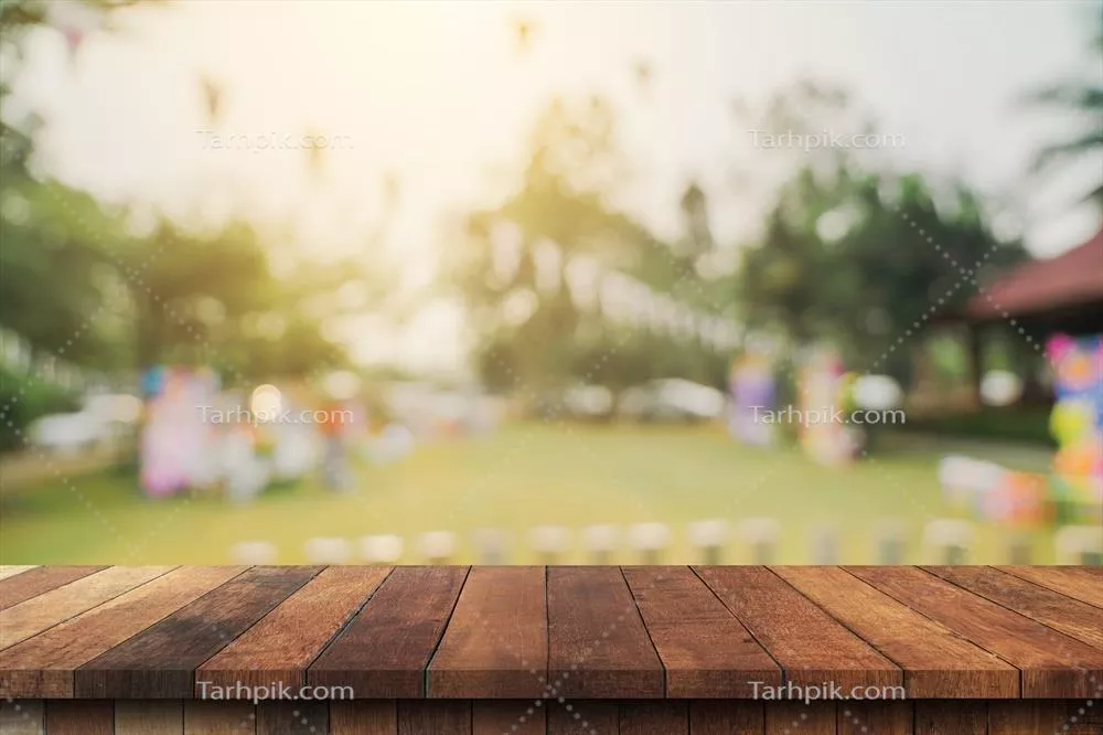 با پسزمینه درختان باغ و نور خورشید: نمایی از بالای میز چوبی خالی