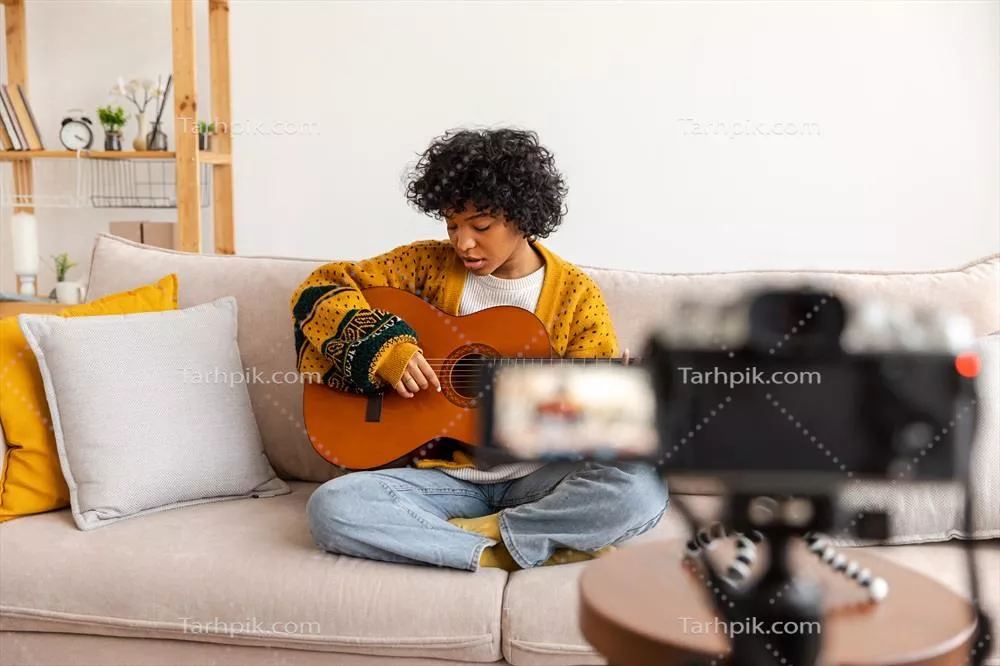 بلاگر گیتاریست: دختر آفریقایی-آمریکایی در حال ویدئو ضبط گیتار و آموزش موسیقی