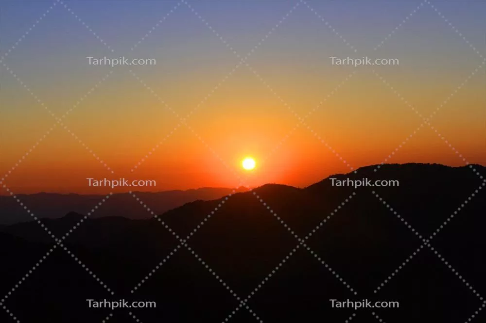 غروب زیبای رنگارنگ در آسمان و ابرها با سیاهه کوهها در زمان غروب