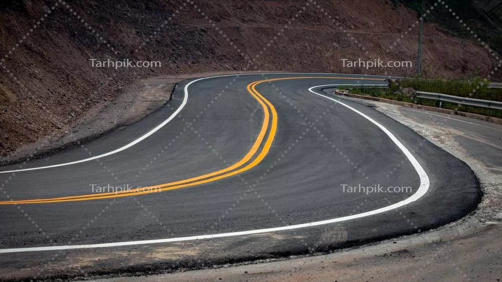 ترافیک زرد و سفید روی آسفالت جاده‌ی کوهستانی با مناظر طبیعی زیبا