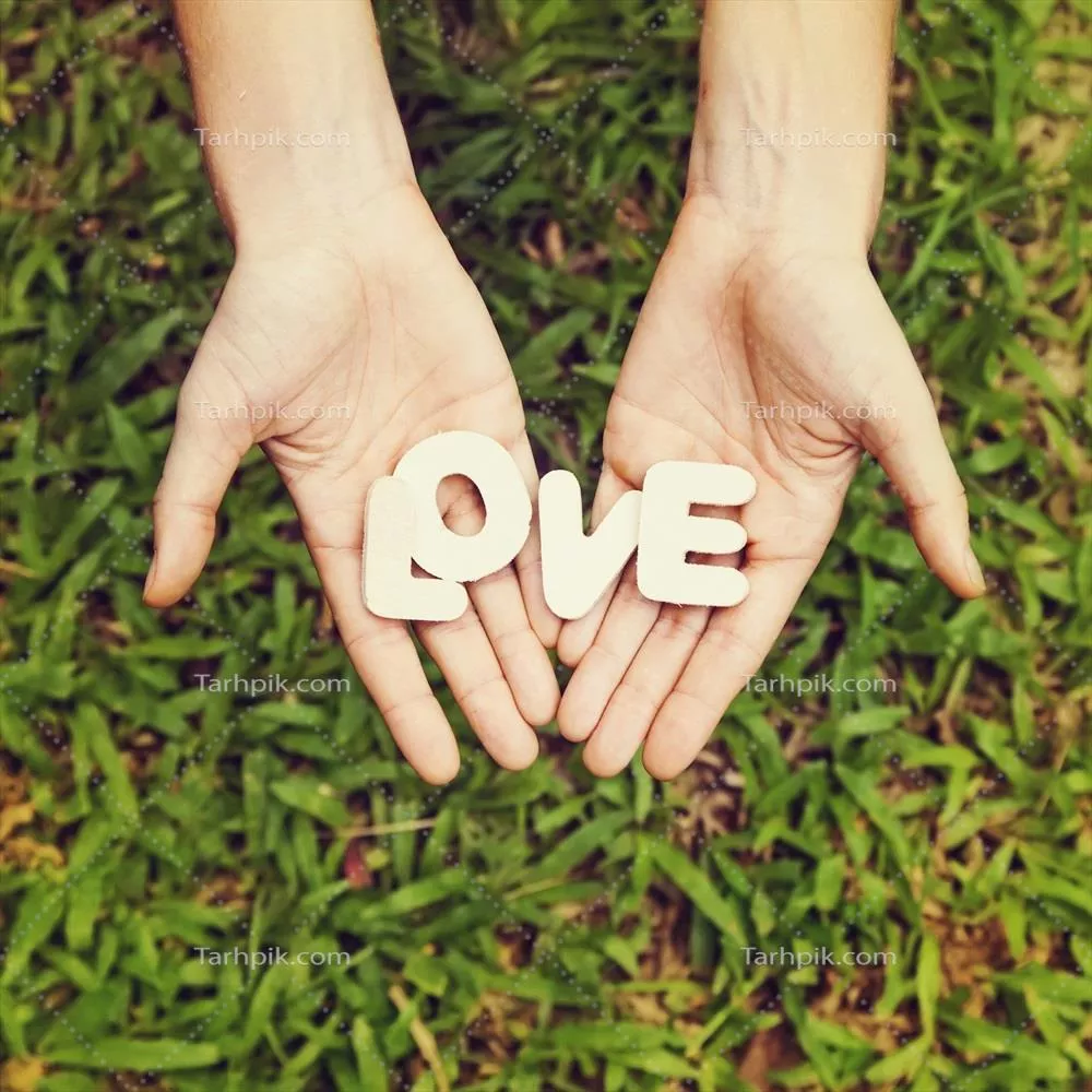زنی که کلمه عشق را در دستانش روی چمن نگه داشته است