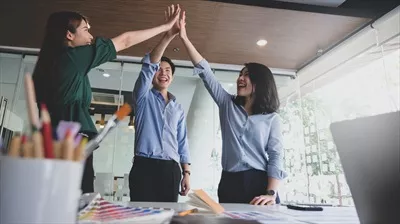 تیم طراح گرافیک با شادی دستهای خود را برای جشن پایان پروژه بالا بردند