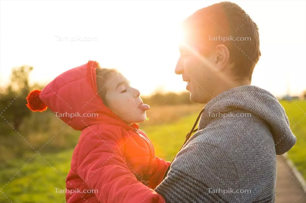 دختر کوچک در ژاکت قرمز با کلاهی که والدش را در آغوش میکشد