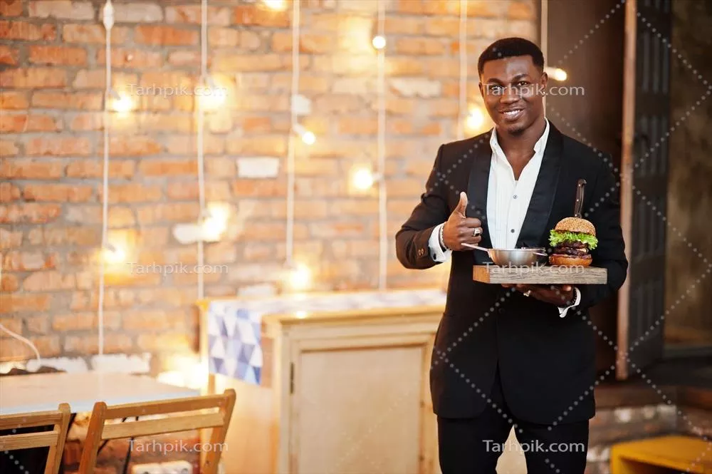 مرد جوان آفریقایی-آمریکایی محترم در کت و شلوار مشکی با سینی همبرگر دوتایی