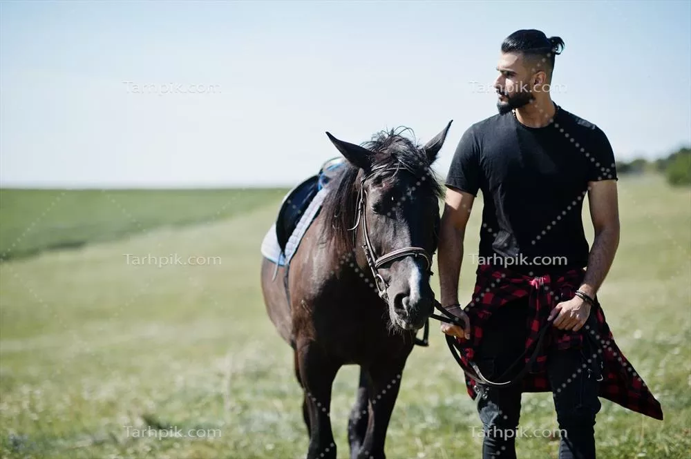 مرد عرب با ریش بلند و پوشش مشکی در کنار اسب عربی خود