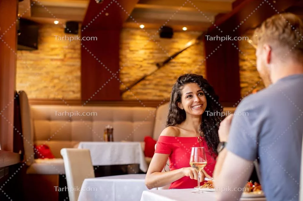 یک زوج جوان در حال صرف ناهار با نوشیدن wine سفید در رستوران