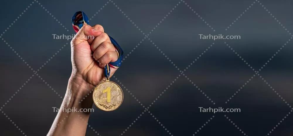 مدال طلا در دست، در پس‌زمینه آسمان غبارآلود و شامگاه