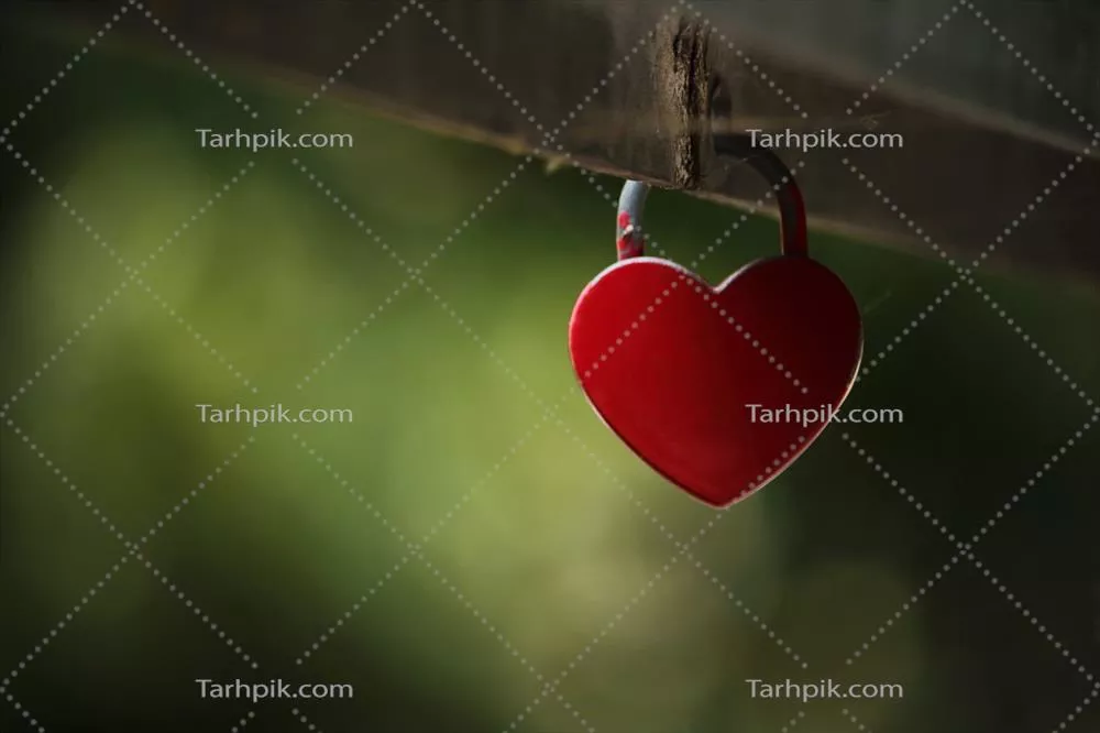 قفل قلبی کوچک قرمز رنگ آویزان از نرده پل