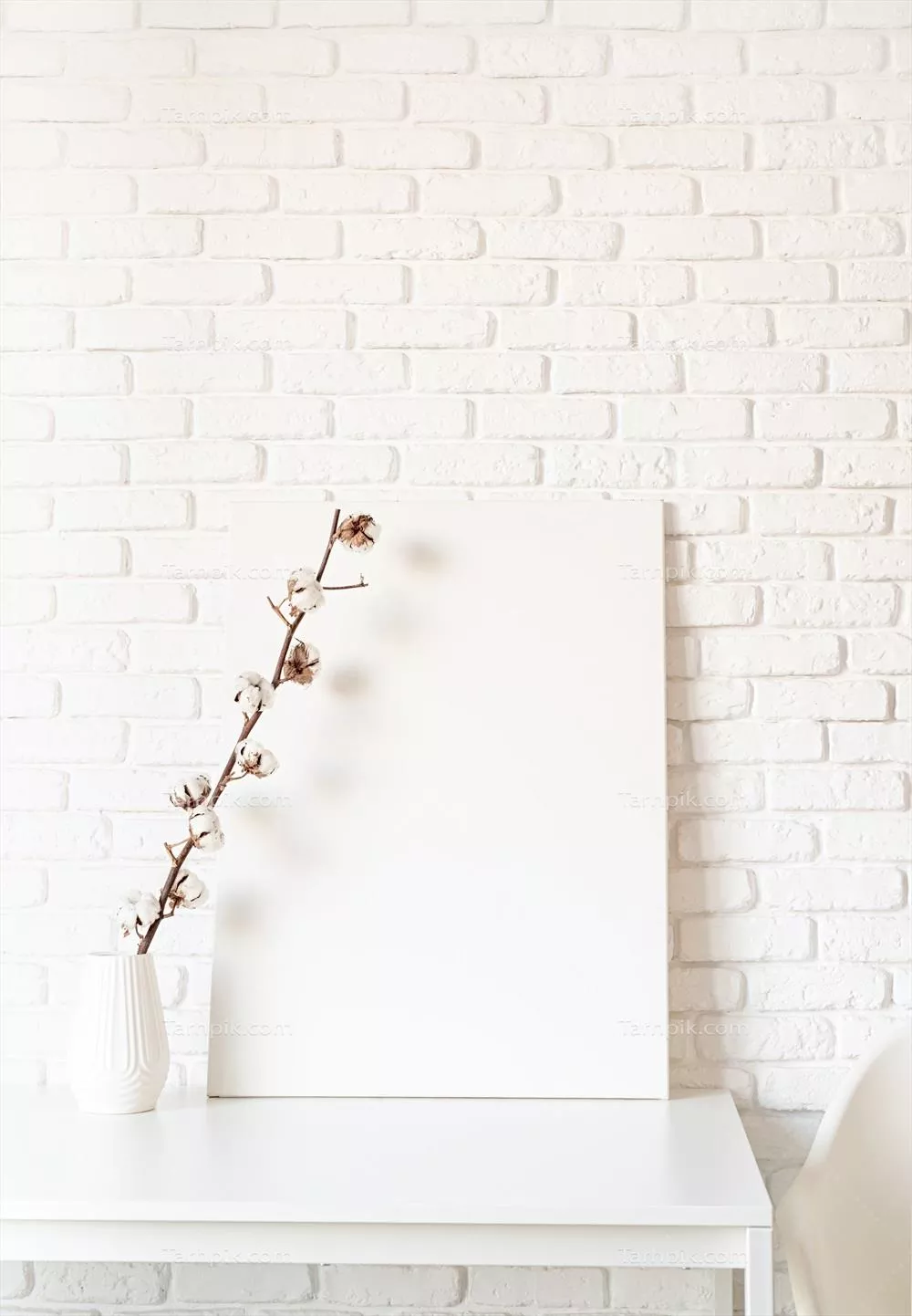 پوستر نمایشی با قاب و شاخه پنبه بر روی پسزمینه دیوار سفید آجری